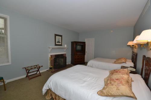 a bedroom with two beds and a fireplace at Century Suites Hotel in Bloomington