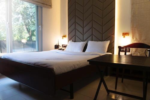 um quarto com uma cama com uma mesa e uma janela em Hotel Cozy Inn em Pune