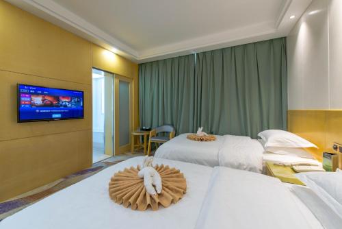a hotel room with two beds and a flat screen tv at Dunhuang Hotel in Dunhuang