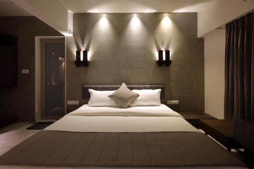 a bedroom with a large bed with lights on the wall at Hotel Carrefour in Ahmedabad