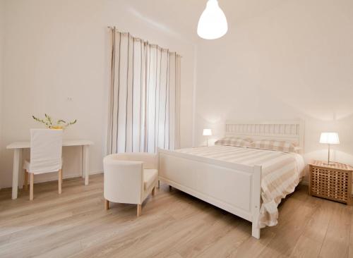 a white bedroom with a bed and a desk at B&B Barone Sieri Pepoli in Trapani