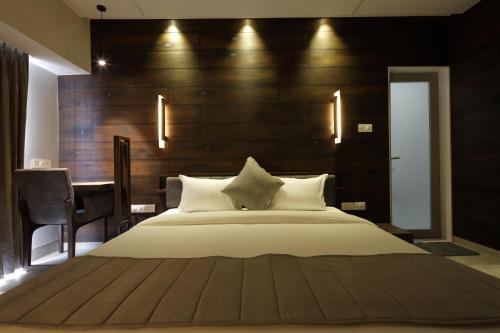 a bedroom with a large bed with a wooden headboard at Hotel Carrefour in Ahmedabad