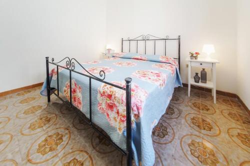 a bedroom with a bed with a floral bedspread at Villetta Martino Guest House in Torre Chianca