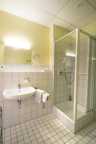 a bathroom with a sink and a shower at Kurparkhotel Das Kleinod in Bad Kissingen