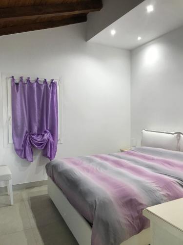 una camera da letto con un letto con lenzuola viola e una finestra di Casa Isabelle a La Spezia