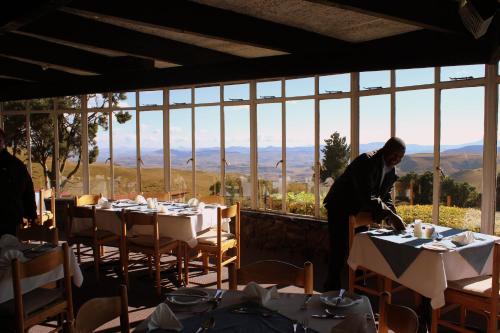 a man standing in front of a dining room with tables at Witsieshoek Mountain Lodge in Phuthaditjhaba