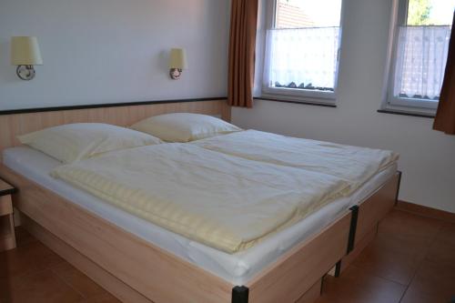 a large bed in a room with two windows at Beim Kahnfährmann in Schlepzig