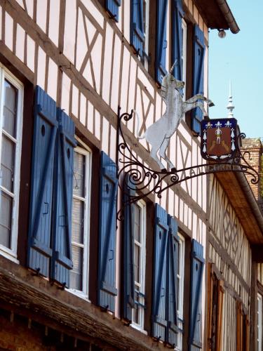 a building with blue windows and a sign on it at Hôtel La Licorne & Spa in Lyons-la-Forêt
