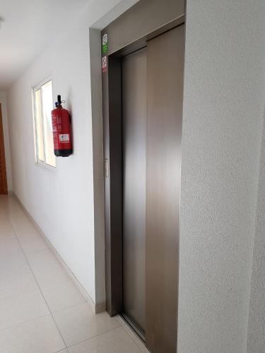a fire extinguisher hanging on a wall next to a door at Atico en playa muchavista san juan Estrella in El Campello