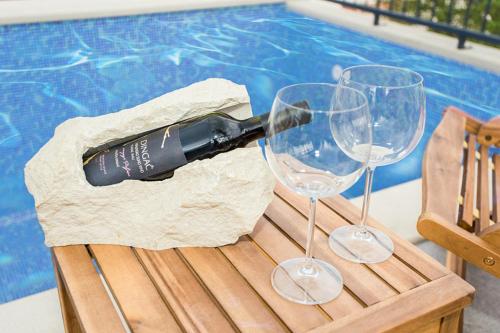two wine glasses sitting on a table next to a swimming pool at Villa Suzy Lux in Sutivan