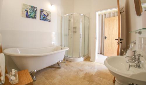 a bathroom with a tub and a shower and a sink at Westfield Country Barns in Braunston