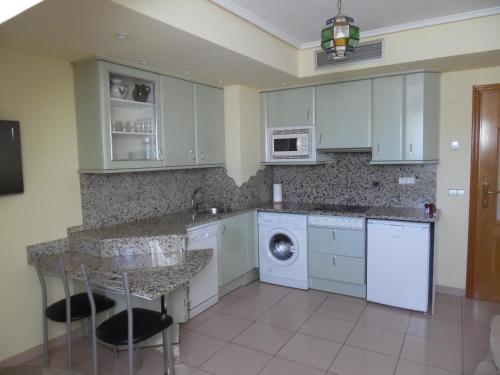 a kitchen with white cabinets and a washer and dryer at Apartamentos Edificio Aguilas in Aínsa