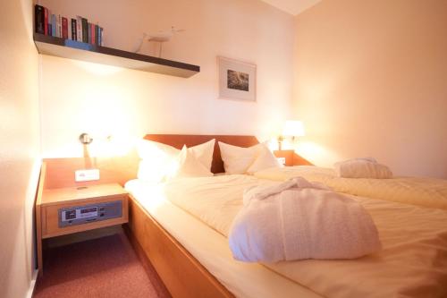 um quarto com uma cama com lençóis brancos e uma mesa de cabeceira em Inselresidenz Strandburg - Ferienwohnung 204 (Ref. 50964) em Juist