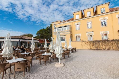 a group of tables with white umbrellas in front of a building at Change The World Hostels - Cascais - Estoril in Monte Estoril
