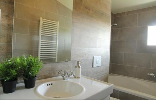 een badkamer met een wastafel, een spiegel en een bad bij Cozy Cottage in Warmenhuizen