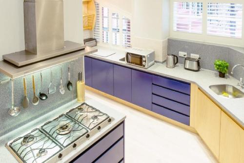 a kitchen with purple cabinets and a stove top oven at Ramsay Gardens - Grand 4-Bedroom Apartment Next To Castle in Edinburgh