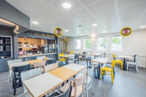 a dining room with tables and chairs in a restaurant at B&B HOTEL Angers 2 Université in Beaucouzé