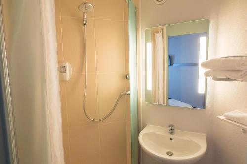 ein Bad mit einem Waschbecken und einer Dusche mit einem Spiegel in der Unterkunft B&B HOTEL Angers 2 Université in Beaucouzé