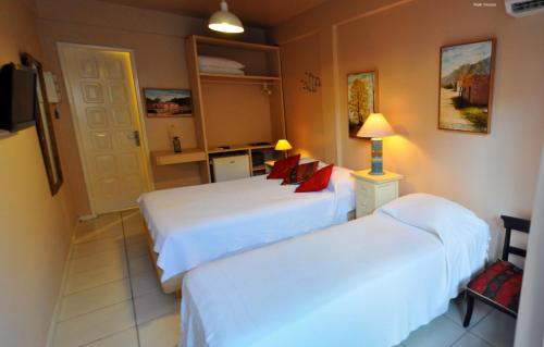 a hotel room with two beds and a television at Pousada Via Brasil in Morro de São Paulo