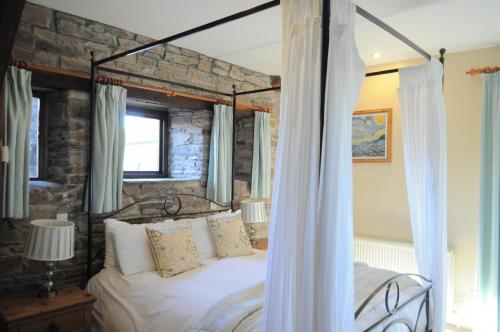 a bedroom with a white bed with a stone wall at Black Mountain Lodge in Glasbury