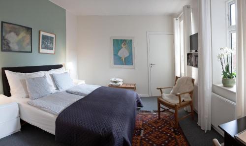 a bedroom with a bed and a chair at Foldenhus Ferieboliger og B&B in Bogense