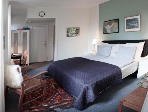a bedroom with a large bed and a chair at Foldenhus Ferieboliger og B&B in Bogense
