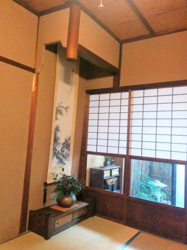 a room with two large windows and a potted plant at Murasakino Guesthouse in Kyoto