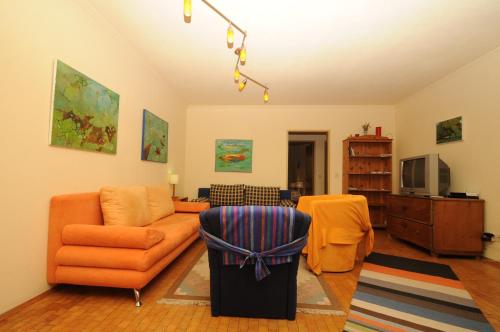 a living room with an orange couch and a tv at Kandolf Apartments Klagenfurt in Klagenfurt