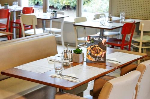 a table in a restaurant with tables and chairs at Campanile NATURE - Epône in Épône