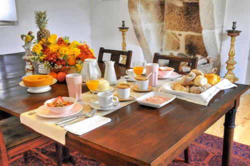 a wooden table with breakfast foods and oranges on it at Casa das Laranjas in Porto