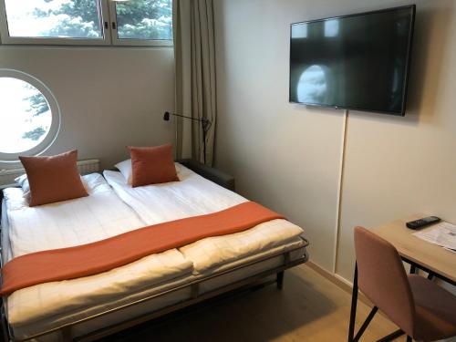 a bedroom with a bed with a flat screen tv on the wall at Pilot Airport Hotel in Vantaa