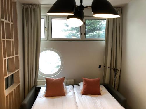 a bedroom with a bed with two pillows and two windows at Pilot Airport Hotel in Vantaa