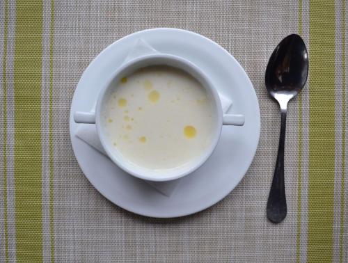a cup of soup on a plate next to a spoon at Hata Hutsula in Mykulychyn