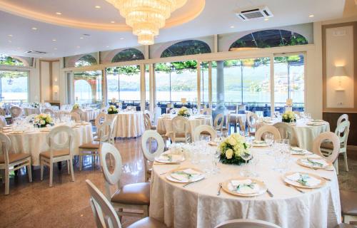 a banquet hall with white tables and chairs and windows at Hotel Leon D'Oro in Orta San Giulio