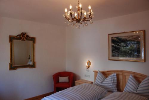 - une chambre avec un lit, un miroir et une chaise dans l'établissement Villa Moroder, à Ortisei