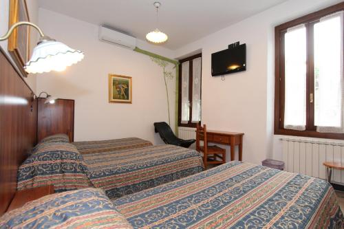 a hotel room with two beds and a television at Albergo Santo Spirito in Molini di Triora