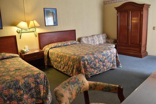 um quarto de hotel com duas camas e uma cadeira em Hotel Ram Val em Zamora de Hidalgo