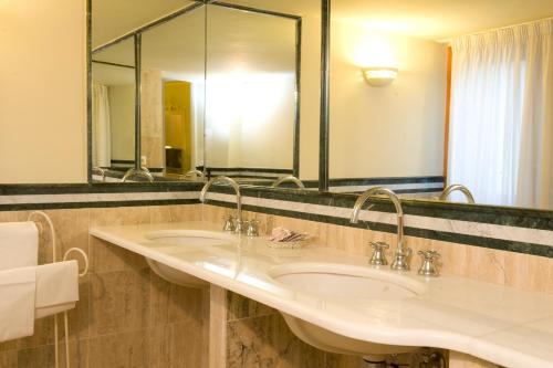 un bagno con due lavandini e un grande specchio di Park Hotel Villaferrata a Grottaferrata
