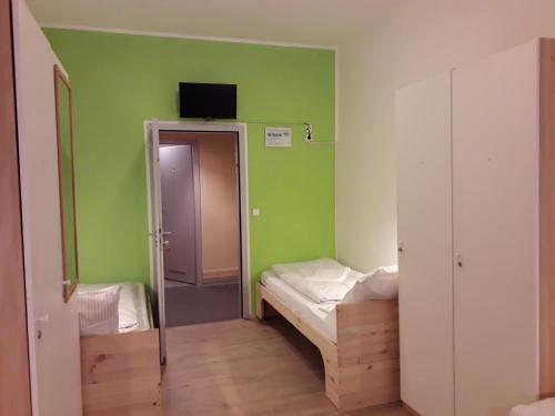 a small room with a bed and a tv on the wall at Hostel Gästehaus Kaiserpassage- Ihr Cityhostel in Karlsruhe