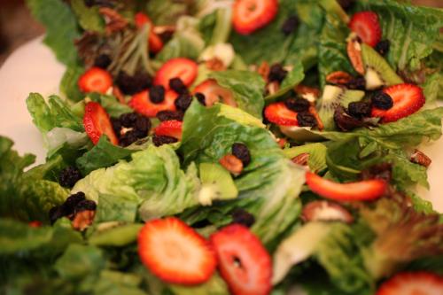 a salad with strawberries and raisins on a plate at Hotel Emily in Pachuca de Soto