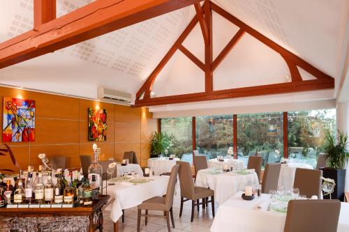 a dining room with white tables and chairs and windows at Logis Hostellerie la Chaumière in Arsonval