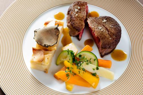 a plate of food with meat and vegetables on it at Logis Hostellerie la Chaumière in Arsonval