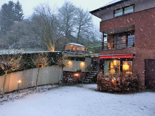 a house with snow on the ground next to a building at B&B Au Roman Païs in Braine-le-Château