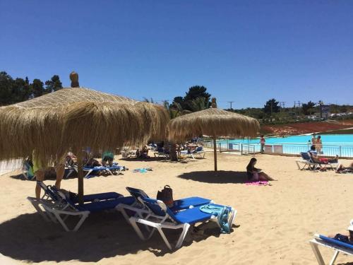 a beach with chairs and straw umbrellas and people at Laguna Bahía, Algarrobo in Algarrobo