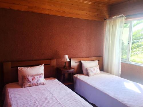 a bedroom with two beds next to a window at Villa Flor do Monte in Lagoa