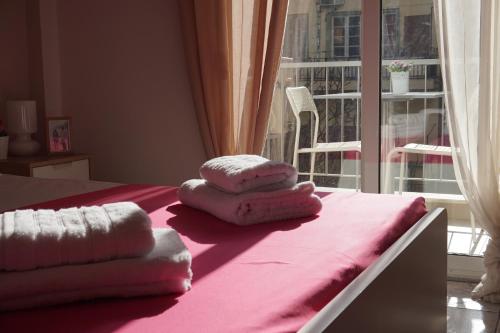 a pile of towels sitting on a bed with a window at Aristotelous Square Luxury Apartment in Thessaloniki