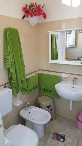 bagno con lavandino, servizi igienici e asciugamani verdi di Mareide a Torre Lapillo