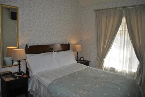 1 dormitorio con 1 cama y 2 ventanas con cortinas en Tinsley House Accommodation, en Cahir