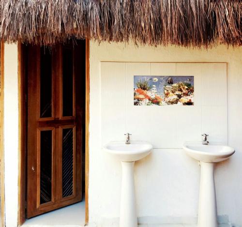 a bathroom with two sinks and a thatch roof at Hostal Nibuni Palomino in Palomino