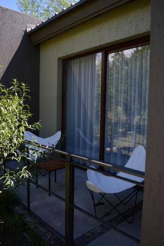 two chairs and a table on a balcony with windows at Posada del Blanco in Potrerillos